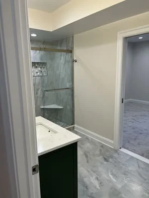 Bathroom with frameless glass shower, marble tile surround and flooring, dark vanity cabinet