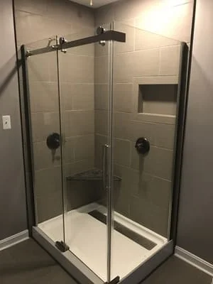 Frameless glass shower enclosure with matte black hardware and ceramic tile surround