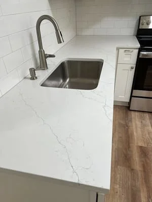 White quartz countertop with stainless steel sink and pull-down faucet, subway tile backsplash