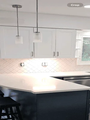 White quartz countertop with geometric pink tile backsplash and dark navy island with pendant lighting
