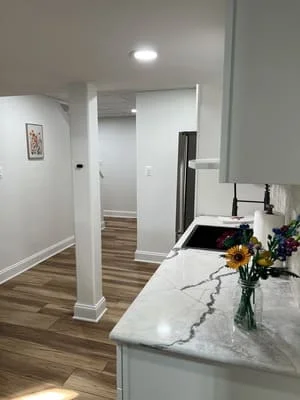 White kitchen island with quartz countertop, recessed lighting, hardwood flooring, and white cabinetry