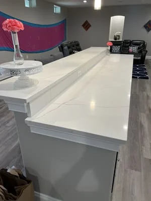 White quartz kitchen countertop with waterfall edge and integrated sink, gray cabinetry base