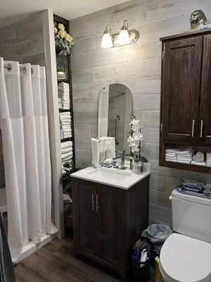 Dark wood vanity with white countertop, subway tile walls, and framed mirror in renovated bathroom