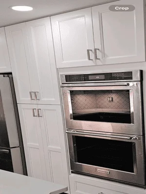 White shaker cabinets with stainless steel double wall ovens and recessed lighting