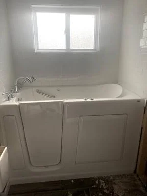 White walk-in bathtub with door entry, grab bars, and handheld showerhead in bathroom
