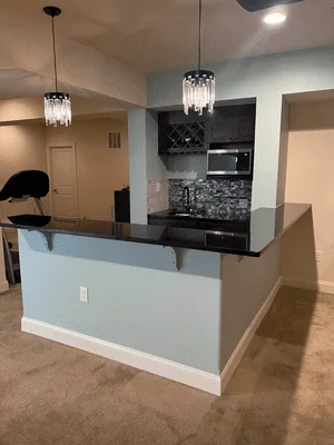 Two-tone kitchen island with blue and white cabinetry, black granite counters, pendant lights, and black appliance wall