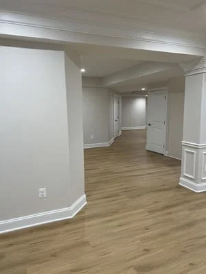 Finished basement with laminate hardwood flooring, white drywall, recessed lighting, and wrapped columns