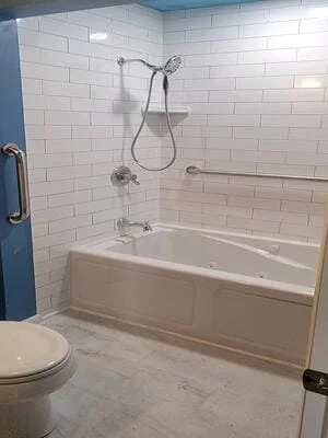 White subway tile bathroom with bathtub, rainfall showerhead, and chrome fixtures