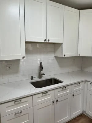 White shaker cabinets with white quartz counters and white subway tile backsplash