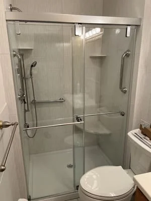 Frameless glass shower enclosure with sliding doors and brushed nickel hardware