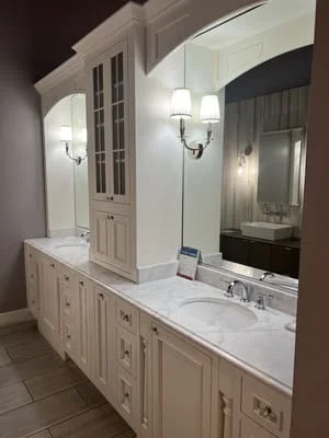 Cream cabinetry double vanity with white marble countertops and large mirror
