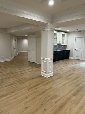 Open concept kitchen with white cabinetry, black countertops, coffered ceiling, and hardwood flooring
