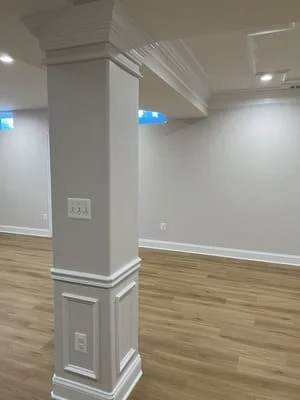 White painted structural column with trim, recessed lighting, and laminate flooring in finished interior space