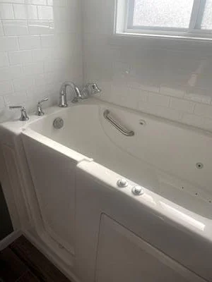 White walk-in tub with grab bars and chrome fixtures against subway tile walls