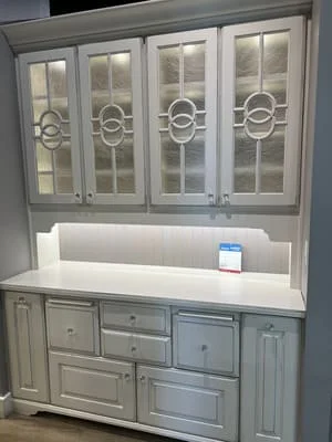 White painted kitchen hutch with glass-front upper cabinets and decorative circular muntins