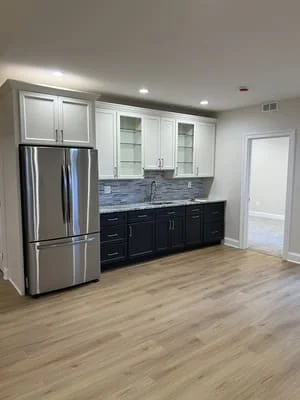 Two-tone kitchen with white and black cabinets, blue tile backsplash, stainless steel appliances