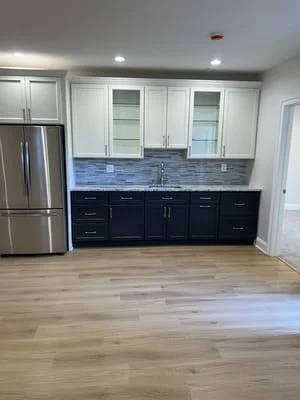 Two-tone kitchen with white and black cabinetry, blue tile backsplash, stainless steel appliances