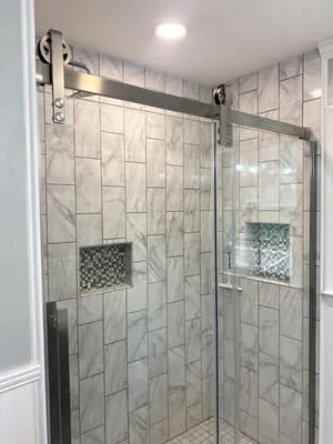 Marble subway tile shower with frameless glass door and brushed nickel hardware