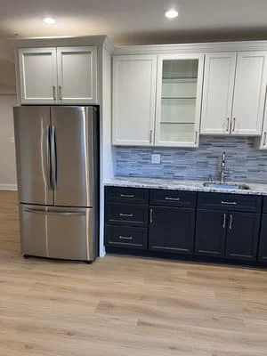 Two-tone kitchen cabinets with blue tile backsplash and stainless steel appliances