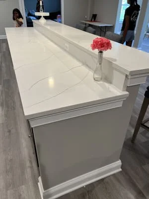 White quartz waterfall island countertop with gray and white cabinetry in modern kitchen