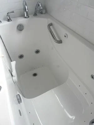 White walk-in bathtub with hydrotherapy jets, grab bars, and chrome fixtures installed