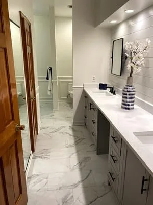 Modern bathroom with marble tile floor, gray vanity, white quartz counters, and subway tile walls