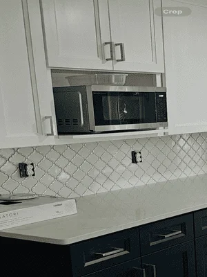 Two-tone kitchen with white and dark cabinets, geometric tile backsplash, and stainless steel appliances